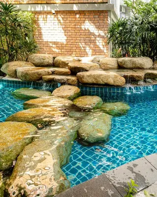 a swimming pool with rocks and a rock wall at Comfy studio - 10 min walk to NaiYang Beach in Nai Yang Beach