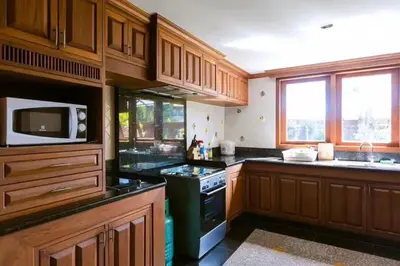 a kitchen with wooden cabinets and a black stove top oven at Classic Cozy Thai Villa BIG pool Party OK in Patong Beach