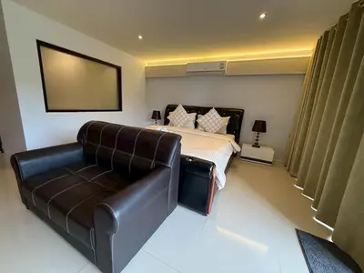 a bedroom with a bed and a leather couch at Studio apartment in Patong, Phuket in Patong Beach