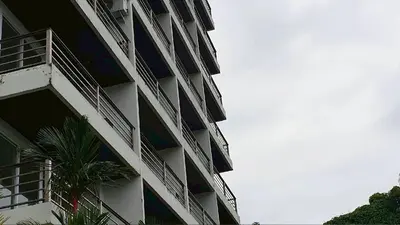 a tall building with a palm tree in front of it at Studio apartment in Patong, Phuket in Patong Beach