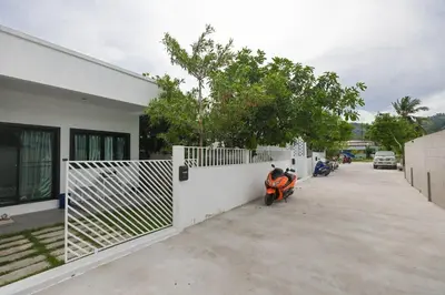 a motorcycle parked in front of a white fence at Ali Cozy Houses in Ban Thalat Choeng Thale
