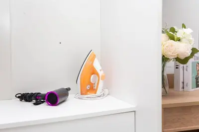 a white shelf with a flashlight and a vase with flowers at Ali Cozy Houses in Ban Thalat Choeng Thale
