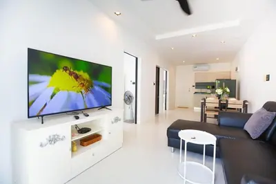a living room with a large flat screen tv on a wall at Ali Cozy Houses in Ban Thalat Choeng Thale