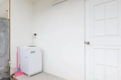 a white refrigerator in a room next to a door at Ali Cozy Houses in Ban Thalat Choeng Thale
