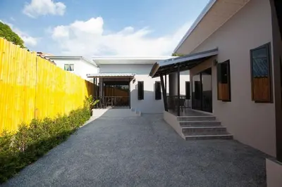 a house with a yellow fence next to a walkway at comfortable BAMBOO houses in Ban Thalat Choeng Thale