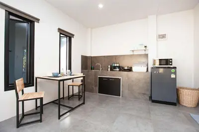 a kitchen with a refrigerator and a table and chairs at comfortable BAMBOO houses in Ban Thalat Choeng Thale
