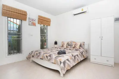 a bedroom with a bed and two windows at cozy Best house with garden near Bang Tao beach in Ban Thalat Choeng Thale
