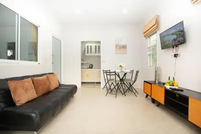 a living room with a black leather couch and a table at cozy Best house with garden near Bang Tao beach in Ban Thalat Choeng Thale