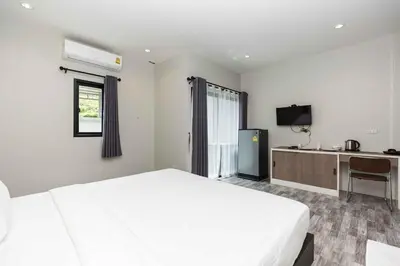 a bedroom with a large white bed and a desk at Cozy Bonaparte Studios in Ban Thalat Choeng Thale