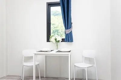 a table with three chairs and a vase with flowers on it at Cozy Bonaparte Studios in Ban Thalat Choeng Thale