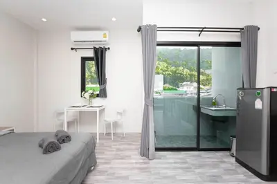 a bedroom with a bed and a bathroom with a sink at Cozy Bonaparte Studios in Ban Thalat Choeng Thale