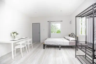 a white bedroom with a bed and a desk at VISUT apartments near mountain in Ban Thalat Choeng Thale