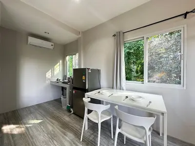 a kitchen with a table and chairs and a refrigerator at VISUT apartments near mountain in Ban Thalat Choeng Thale