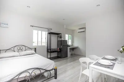 a bedroom with a white bed and a table and chairs at VISUT apartments near mountain in Ban Thalat Choeng Thale