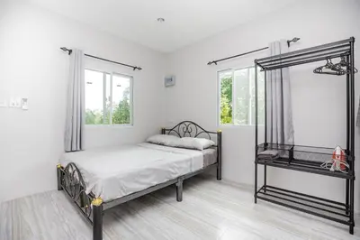 a white bedroom with a bed and a window at VISUT apartments near mountain in Ban Thalat Choeng Thale