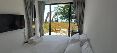 a bedroom with a white bed with a large window at Sunrise Beachfront Rawai in Ban Saiyuan (1)