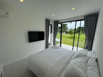 a bedroom with a white bed and a television at Sunrise Beachfront Rawai in Ban Saiyuan (1)