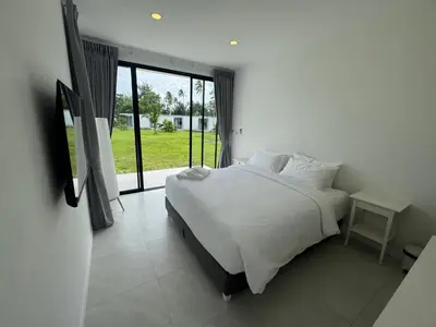 a bedroom with a white bed and a large window at Sunrise Beachfront Rawai in Ban Saiyuan (1)