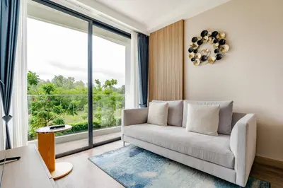 a living room with a couch and a large window at Laya Resort Garden Escape- Tropical Serenity Suite in Layan Beach