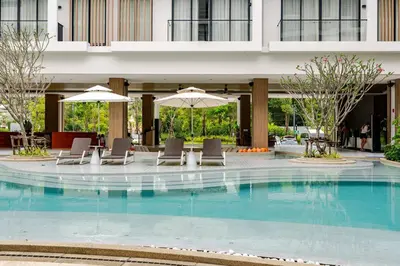 a pool with chairs and umbrellas in a building at Laya Resort Garden Escape- Tropical Serenity Suite in Layan Beach