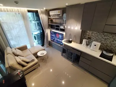 a living room with a couch and a kitchen at Tropical bliss & serenity in CityGate Resort near Kamala Beach in Phuket Town