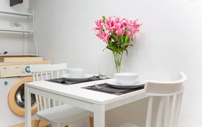 a white table with a vase of pink flowers on it at Waterfall House, 800 m to the Bang Tao beach in Ban Thalat Choeng Thale