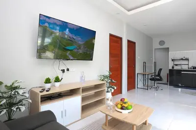 a living room with a couch and a tv on the wall at GA-GA-GA A cozy house in a quiet location on Bang Tao Beach in Ban Thalat Choeng Thale