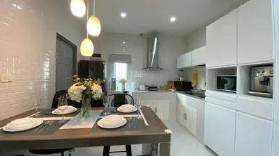 a kitchen with a table with plates and flowers on it at Cozy 2-bedrooms houses complex DIN, Bang Tao beach in Ban Thalat Choeng Thale