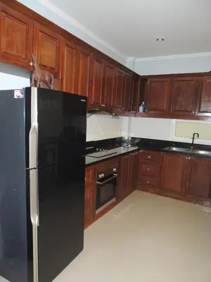 a kitchen with a black refrigerator and wooden cabinets at The Trend Villa in Kamala Beach
