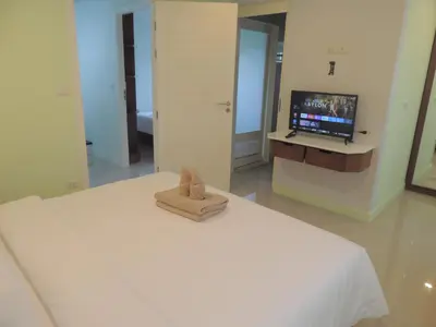 a bedroom with a white bed with a tv on the wall at The Trend Villa in Kamala Beach