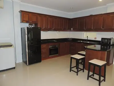 a kitchen with wooden cabinets and a black refrigerator at The Trend Villa in Kamala Beach