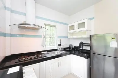 a kitchen with white cabinets and a stainless steel refrigerator at BAN House, Bang Tao beach in Ban Thalat Choeng Thale