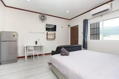 a bedroom with a bed and a table and a window at DUCATTI apartments, 10 min to Bang Tao beach in Ban Thalat Choeng Thale