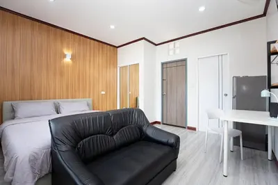 a bedroom with a bed and a black leather couch at DUCATTI apartments, 10 min to Bang Tao beach in Ban Thalat Choeng Thale