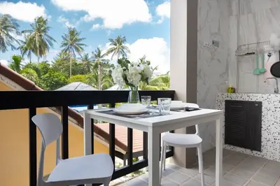 a white table and chairs in a room with a balcony at DUCATTI apartments, 10 min to Bang Tao beach in Ban Thalat Choeng Thale