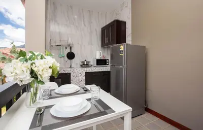 a kitchen with a table with plates and a refrigerator at DUCATTI apartments, 10 min to Bang Tao beach in Ban Thalat Choeng Thale