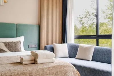 a bedroom with a bed and a couch and a window at Laya Resort -Tropical Studio in Layan Beach