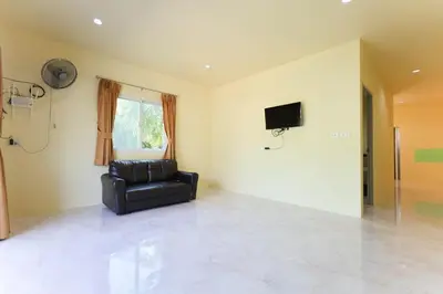 a living room with a chair and a television at Yellow apartments 46,47 in Ban Thalat Choeng Thale