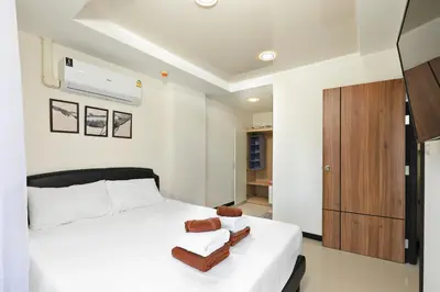 a bedroom with a white bed and a wooden cabinet at Comfy 1-BR room Mountain View, 5 min to Rawai Beach in Phuket Town