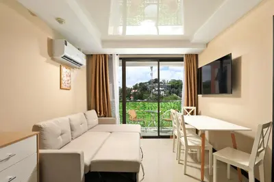 a living room with a couch and a table and a dining room at Comfy 1-BR room Mountain View, 5 min to Rawai Beach in Phuket Town