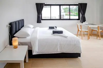 a bedroom with a white bed and a table at Stay White Orchid in Krabi town