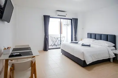a bedroom with a bed and a desk and a window at Stay White Orchid in Krabi town