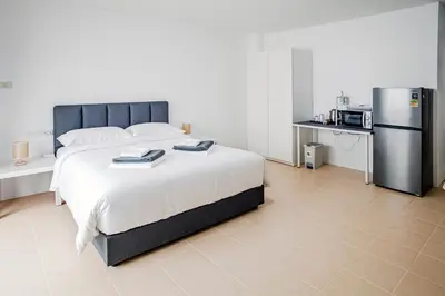 a bedroom with a large bed and a refrigerator at Stay White Orchid in Krabi town
