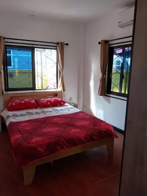 a bedroom with a bed with red pillows and two windows at House in the heart of Kamala in Kamala Beach