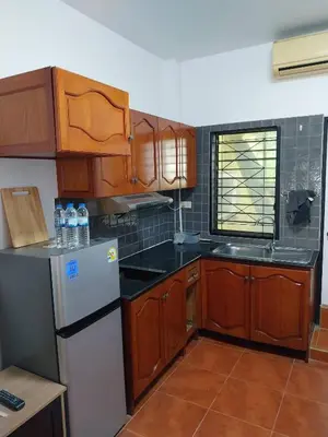a kitchen with wooden cabinets and a white refrigerator at House in the heart of Kamala in Kamala Beach