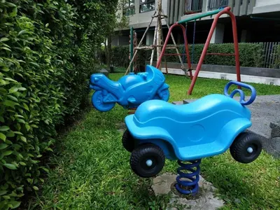 two blue toy cars sitting in the grass next to a swing at Zcape 1 bedroom apartment in Ban Thalat Choeng Thale