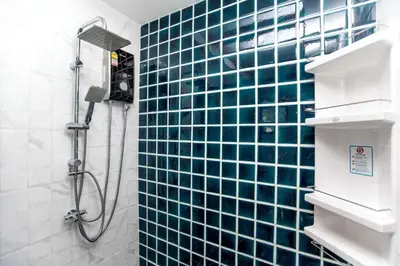 a bathroom with a shower with blue tiles on the wall at Cat house, 5 min to the beach in Ban Thalat Choeng Thale