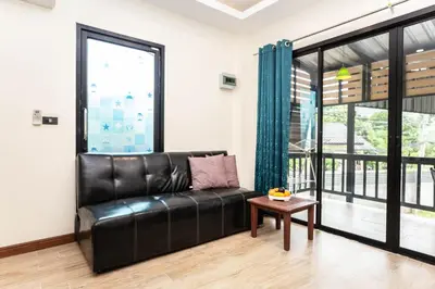 a black leather couch in a living room with a table at Cat house, 5 min to the beach in Ban Thalat Choeng Thale
