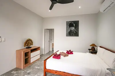 a bedroom with a bed and a dresser and a clock at Suwali Villa - 3 Bedroom Private Pool Villa in Ban Saiyuan (1)
