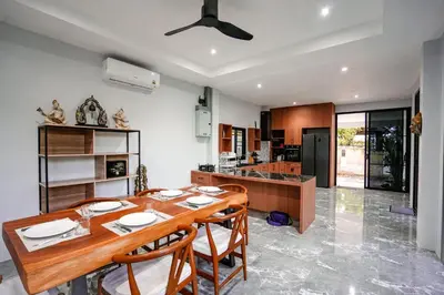 a kitchen and dining room with a wooden table and chairs at Suwali Villa - 3 Bedroom Private Pool Villa in Ban Saiyuan (1)